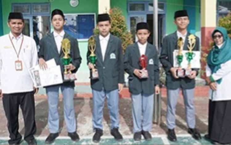 Empat peserta didik MAN Kapuas bersama para guru saat menunjukan piala berhasil diraih di Turnamen Karate Piala Dandim 1011 Kuala Kapuas. (FOTO: MAN KAPUAS)