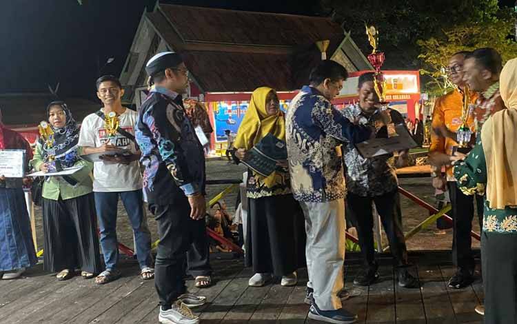 Wakil Bupati Sukamara, Ahmadi menyerahkan hadoah kepada pemenang lomba dalam acara Sukamara Expo 2022, Sabtu, 22 Oktober 2022. (FOTO:NORHASANAH)