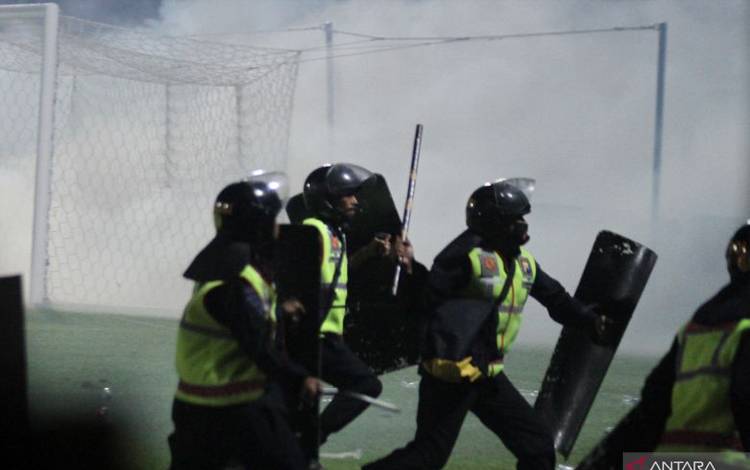 Aparat keamanan berusaha menghalau suporter yang masuk ke lapangan usai pertandingan BRI Liga 1 antara Arema melawan Persebaya di Stadion Kanjuruhan, Malang, Jawa Timur, Sabtu malam (1/10/2022). Polda Jatim mencatat jumlah korban jiwa dalam kerusuhan tersebut sementara sebanyak 127 orang. ANTARA FOTO/Ari Bowo Sucipto/foc.