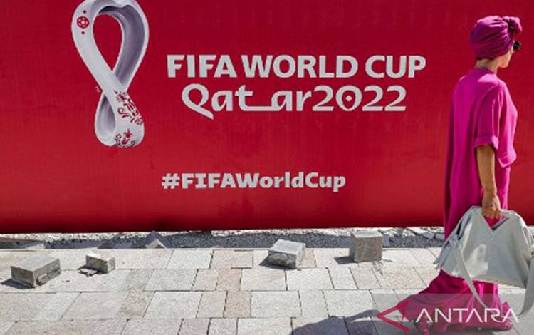 Arsip foto - Seorang wanita berjalan di depan baliho besar logo Piala Dunia FIFA 2022 di West Bay Doha, Qatar, pada 13 Oktober 2022. ANTARA/AFP/Giuseppe Cacace/pri.
