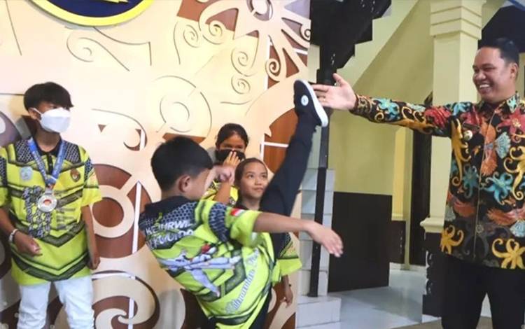 Muhammad Ilham menunjukkan bakatnya memainkan jurus Taekwondo di hadapan Bupati Lamandau Hendra Lesmana. (FOTO: HENDI NURFALAH)