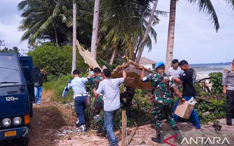 Tampak petugas Lanud Raden Sadjad saat mengamankan puing diduga mirip badan pesawat yang ditemukan warga di Pantai Air Danau, Sejuba, Desa Sepempang, Bunguran Timur, Natuna, Kepri, Sabtu (24/12). (ANTARA/Cherman)