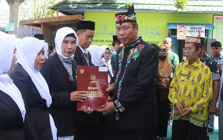 Dua guru MTsN 2 Kapuas saat menerima tanda kehormatan Satya Lencana Karya Satya, baru-baru ini. (FOTO: IST)