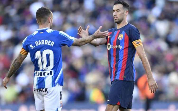 Gelandang Barcelona Sergio Busquets (kanan) bersalaman dengan gelandang Espanyol Sergi Darder pada akhir pertandingan LaLiga antara FC Barcelona dan RCD Espanyol di Stadion Camp Nou di Barcelona pada 31 Desember 2022. (Photo by Pau BARRENA / AFP) (AFP/PAU BARRENA)
