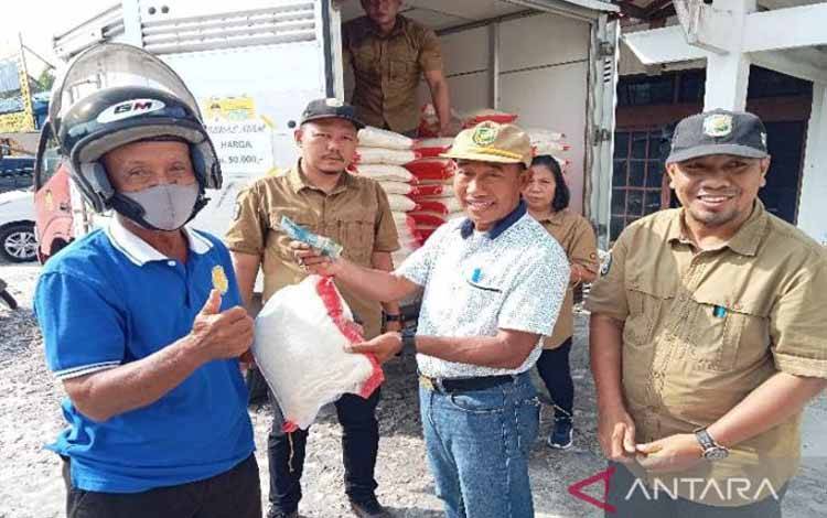 Kepala DPKUKMP Palangka Raya Samsul Rizal menyerahkan secara simbolis kepada warga yang membeli beras murah yang disediakan instansi terkait di Jalan Ahmad Yani, Jumat (13/1/2023). ANTARA/Adi Wibowo
