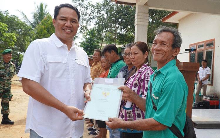 Bupati Lamandau Hendra Lesmana menyerahkan secara simbolis sertifikat tanah Program Redistribusi Tanah kepada warga di Desa Batu Hambawang, Kecamatan Sematu Jaya, Senin, 16 Januari 2023. (FOTO : HENDI NURFALAH)