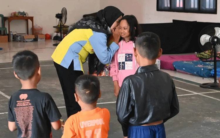 Salah satu pegawai DP3AP2KB Kabupaten Lamandau tengah memberikan pendampingan berupa terapi trauma healing bagi anak korban bencana. (FOTO : HENDI NURFALAH)