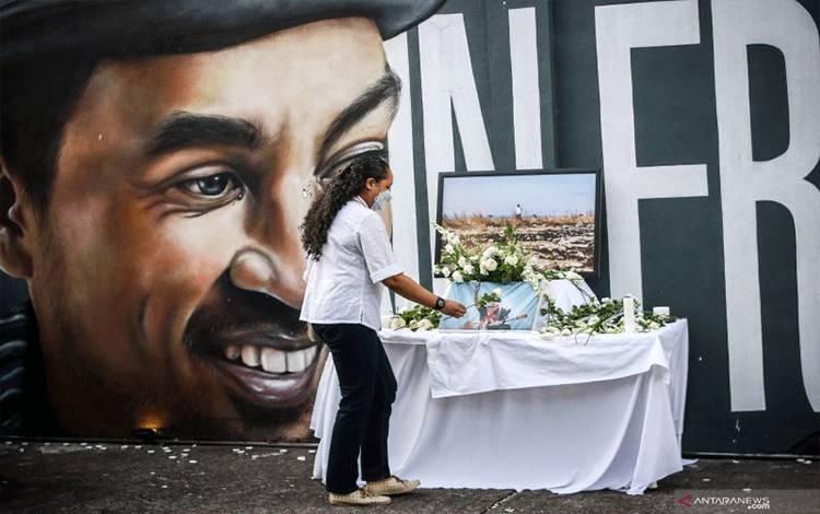 Penggemar meletakan bunga di depan mural penyanyi almarhum Glenn Fredly dalam acara "Kasih di Hari Putih" di M Bloc, Jakarta, Kamis (8/4/2021). Acara tersebut untuk mengenang satu tahun kepergian Glenn Fredly. ANTARA FOTO/Rivan Awal Lingga/wsj.