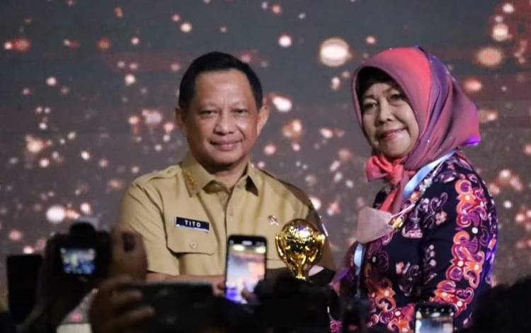 Mendagri Tito Karnavian menyerahkan penghargaan UHC Award kepada Asisten 1 Setda Kota Palangka Raya. (FOTO: HUMAS)