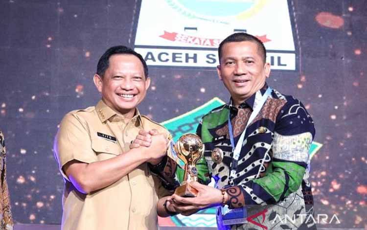 Bupati Kepulauan Meranti Muhammad Adil (kanan) saat menerima penghargaan Universal Health Coverage yang diserahkan Menteri Dalam Negeri Tito Karnavian di Jakarta, Selasa (14/3/2023). (ANTARA/HO-Prokopim Setda Kepulauan Meranti)