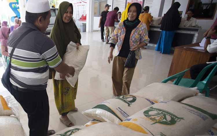 Petugas menyerahkan beras kepada Keluarga Penerima Manfaat (KPM) saat penyaluran bantuan sosial beras di Indramayu, Jawa Barat, Rabu (31/5/2023). Badan Pangan Nasional (Bapanas) melalui PT Pos Indonesia menyalurkan beras bantuan kepada 21,3 juta KPM di 38 provinsi dari April hingga Mei 2023 dengan jumlah total beras yang didistribusikan sebanyak 640.590 ton. ANTARA FOTO/Dedhez Anggara/nym