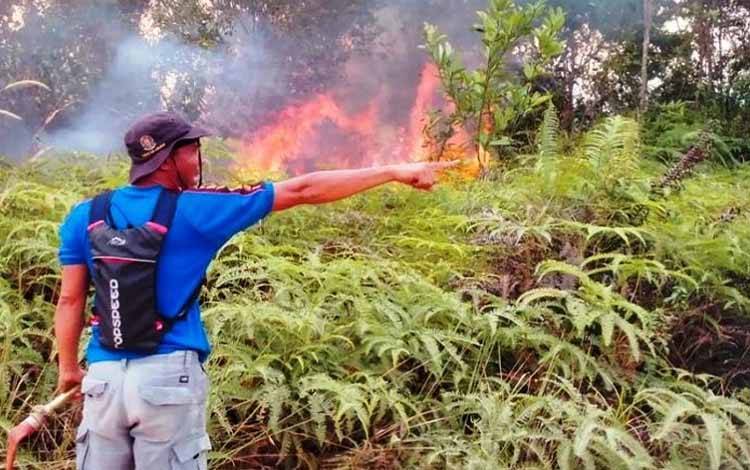 Salah satu petugas BPBD Kabupaten Lamandau tengah berusaha memadamkan api yang membakar lahan kosong di sekitar gedung balai pertanian setempat. (FOTO: HENDI NURFALAH)