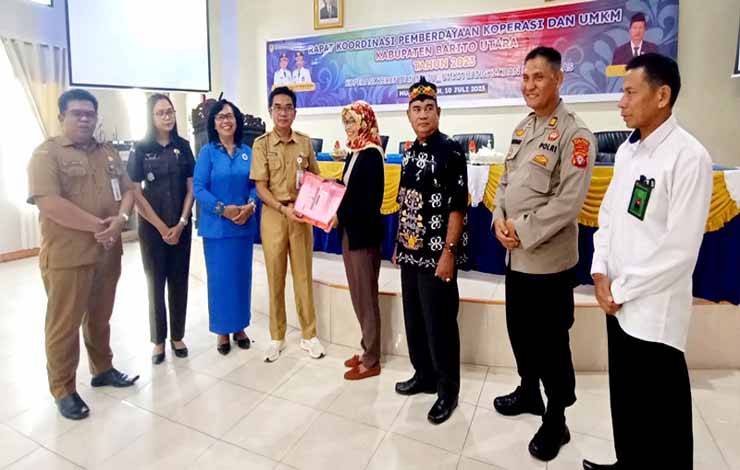 Asisten I bidang pemerintahan Barito Utara, Eveready Noor didampingi Kadis Nakertranskop UKM, M Mastur dan mewakili unsur FKPD saat menyerahkan materi rapat koordinasi kepada perwakilan peserta rakor, di aula BappedaLitbang, Senin 10 Juli 2023. (foto: dhani)