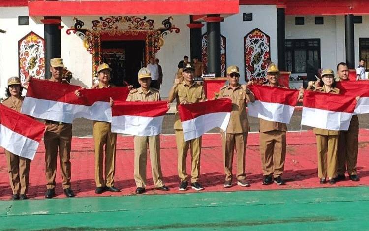 Bupati Murung Raya Perdie M. Yoseph foto bersama Kepala Dinas/Badan dan bendera merah putih yang telah mereka sumbangkan di halaman kantor Bupati Murung Raya.