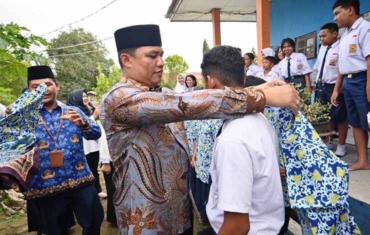 Bupati Hendra Lesmana membagikan baju batik khas Kabupaten Lamandau kepada salah satu peserta didik. (FOTO : HENDI NURFALAH)