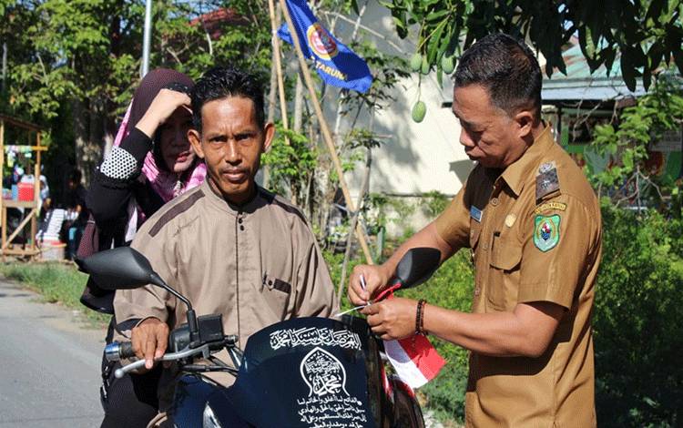 Pembagian bendera kepada warga melintas di Desa Sei Asem, Kecamatan Kapuas Hilir. (FOTO: IST)