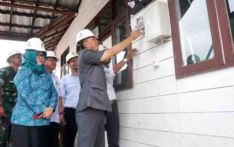 Bupati Barito Utara H Nadalsyah didampingi Ketua TP PKK Hj Sri Hidayati dan pihak PLN saat menyalakan saklar listrik di salah satu desa belum lama ini. (FOTO: DHANI)
