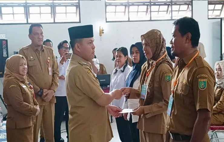 Pj Bupati Barsel, Deddy Winarwan mengalungkan tanda peserta tanda dimulainya workshop peningkatan kompetensi PPL. (FOTO : URIUTU DJAPER)