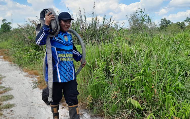 Petugas lapangan saat membawa gulungan selang air pasca-memadamkan api Karhutla di wilayah Kota Palangka Raya. (FOTO: MARINI)