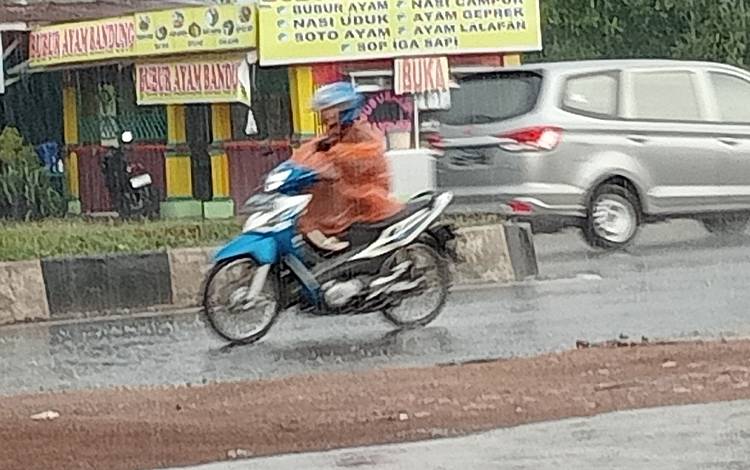 Seorang pengendara mengenakan jas hujan menerobos hujan yang mengguyur Kota Palangka Raya pada Rabu, 6 September 2023. (FOTO: TESTI PRISCILLA)