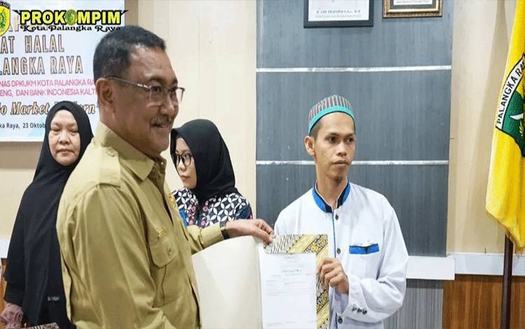 Plh Sekda Palangka Raya, Sahdin Hasan menyerahkan sertifikat halal kepada UMKM. (FOTO: HUMAS)