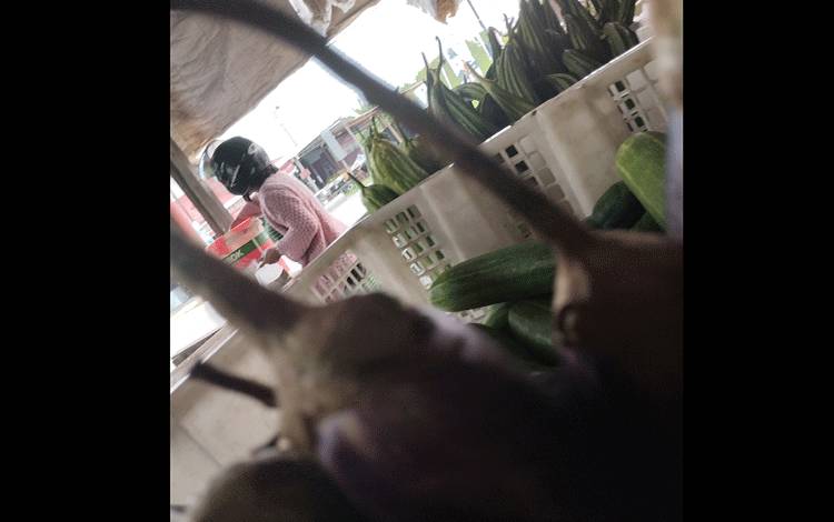 Pembeli memilih tahu dari beberapa komoditi yang dijual di salah warung sayur di Kota Palangka Raya. Tampak juga aneka sayur yang dijual, salah satunya timun.(FOTO: TESTI PRISCILLA)