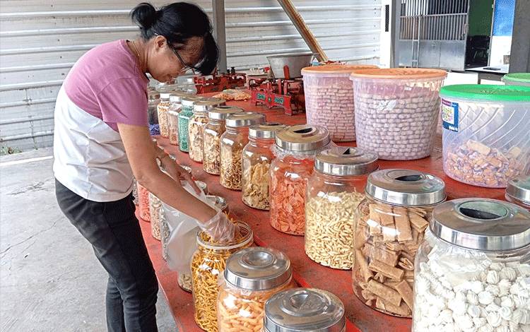 Penjual kue mengambil dan menimbang kue yang ingin dibeli pengunjung di salah satu toko kue kering di Palangka Raya, Rabu, 1 November 2023. (FOTO: TESTI PRISCILLA)