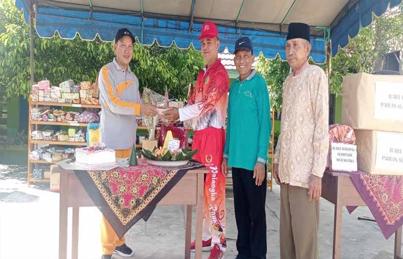 Lurah Banturung di dampingi Kepala Madrasah sambil diiringi lagu ulang tahun lalu memberikannya kepada siswa dan guru pada Sabtu, 25 November 2023.(FOTO: TESTI PRISCILLA)