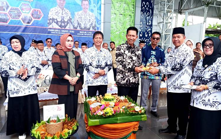 Ketua PGRI Barito Utara Maslan menyerahkan nasi tumpeng kepada mantan Bupati Barito Utara periode 2018-2023, H Nadalsyah pada peringatan HUT PGRI ke 78 dan HGN tahun 2023 di arena Tiara Batara Muara Teweh, Selasa 28 November 2023. (FOTO: DHANI)