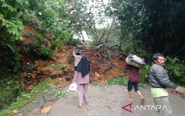 Sejumlah orang melewati jalan raya yang tertimbun longsor di Nagari Lolo, Kecamatan Pantai Cermin, Kabupaten Solok, Sumatera Barat dengan berjalan kaki. (ANTARA/HO-Diskominfo Solok)