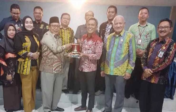 Kepala Dinas PMD Kapuas, Budi Kurniawan saat menerima cinderamata dari legislator Kabupaten Tabalong, bertempat di Aula Dinas PMD Kapuas. (FOTO: IST)