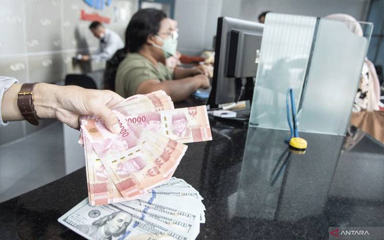 Petugas menunjukan uang pecahan rupiah dan dolar AS di gerai penukaran mata uang asing VIP (Valuta Inti Prima) Money Changer, Jakarta, Selasa (3/1/2023). ANTARA FOTO/Muhammad Adimaja/foc.