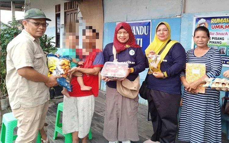 Sekretaris Dinas Perikanan Palangka Raya Sri Utomo saat menyerahkan bantuan sembako kepada orang tua anak berisiko stunting di jalan mendawai (Foto : PATHUR)