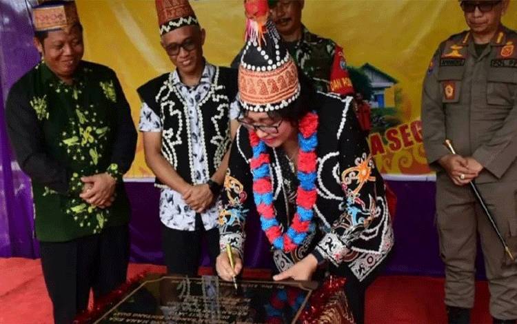 Penjabat Bupati Lamandau Lilis Suriani manandatangani prasasti saat meresmikan rumah adat Macan Sangar Bintang Dua. (FOTO : HENDI NURFALAH)