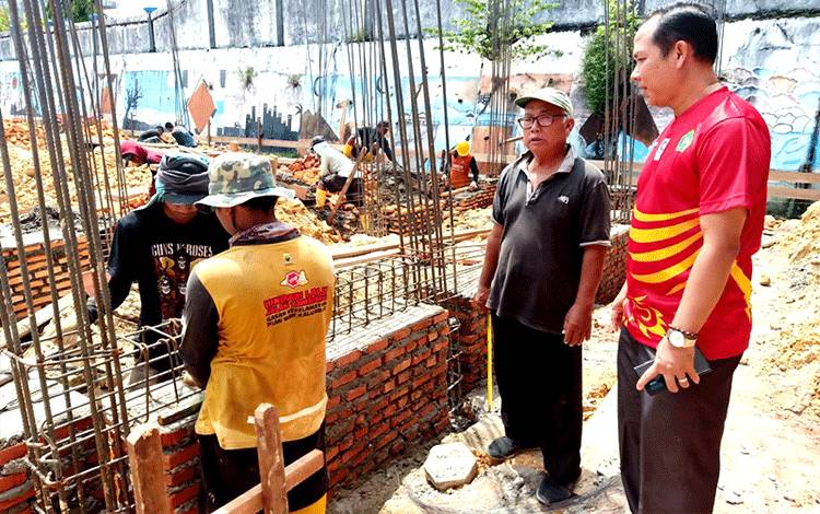 Kepala MTsN Barito Utara, Satia Rahman bersama pengawas bangunan Ruang Kelas Baru (RKB) saat meninjau para pekerja bangunan di lokasi proyek, Sabtu 23 Maret 2023. (Foto: Dhani)