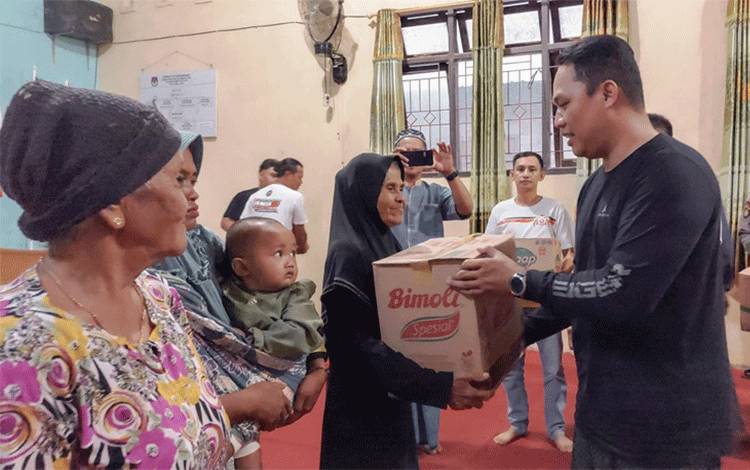 Pembina KLC Hendra Lesmana menyalurkan paket sembako pada kegiatan Baksos di Desa Bukit Raya, Kecamatan Menthobi Raya. (FOTO : HENDI NURFALAH)