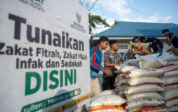 Petugas menurunkan beras dari kendaraan untuk dibagikan kepada mustahik di Kantor Badan Amil Zakat Nasional (Baznas) di Palu, Sulawesi Tengah, Sabtu (23/3/2024). (ANTARA FOTO/Basri Marzuki/rwa.)