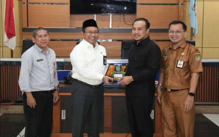 Sekda Banjar Mokhamad Hilman (kedua kiri) menyerahkan cenderamata kepada Wakil Ketua I DPRD Barito Utara Kalteng Permana Setiawan (kedua kanan) saat kunjungan kerja di Kabupaten Banjar, Kalimantan Selatan, Senin (20/5/2024). (ANTARA/HO-Pemkab Banjar)