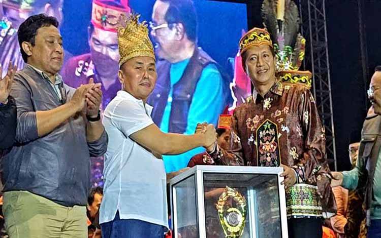 Gubernur Kalteng Sugianto Sabran menyerahkan piala bergilir kepada Pj Bupati Barito Utara, Muhlis pada penutupan FBIM tahun 2024, Jumat malam 24 Mei 2024 di halaman Indoor Serbaguna Jalan Tjilik Riwut KM 5.(foto: Dhani)