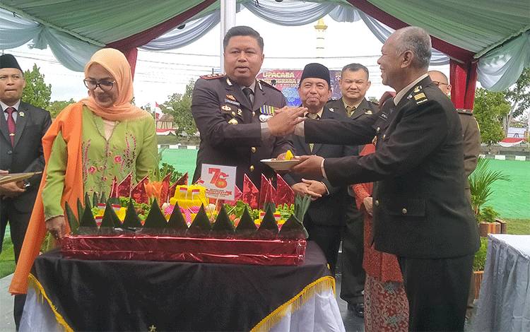 Kapolres Sukamara, AKBP Telly Alvin memberikan potongan tumpeng kepada anggota tertua Polres Sukamara. Senin, 1 Juli 2024. (FOTO:NORHASANAH)