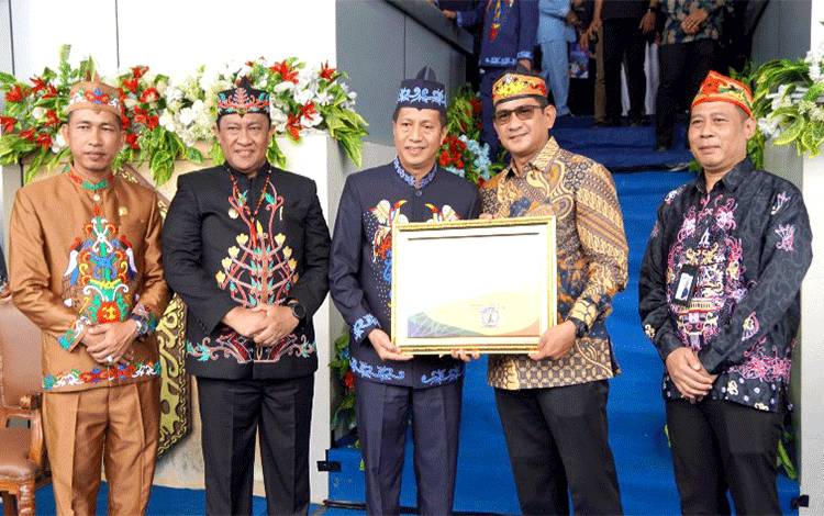 Pj Bupati Barito Utara Muchlis menerima piagam penghargaan UHC yang diserahkan oleh Deputi Direksi Wilayah VIII BPJS Kesehatan, Nuim Mubaraq didampingi Kepala BPJS Kesehatan Cabang Muara Teweh, Achmad Zainuddin, Wakil Gubernur Kalteng H Edy Pratowo dan Wakil Ketua II DPRD Kalteng H Jimmy Carter usai peringatan Hari Jadi ke 74 Kabupaten Barito Utara, di arena Tiara Batara Muara Teweh, Senin, 22 Juli 2024. (Foto: Dhani)