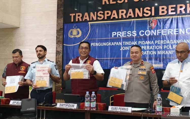Direktur Tindak Pidana Umum (Dirtipidum) Bareskrim Polri Brigjen Pol Djuhandhani Rahardjo Puro (tengah) bersama perwakilan AFP Luke Nasir dan anggota Polri lainnya menunjukkan barang bukti yang disita dalam konferensi pers pengungkapan kasus TPPO di Gedung Bareskrim Polri, Jakarta, Selasa (23/7/2024). ANTARA/Nadia Putri Rahmani