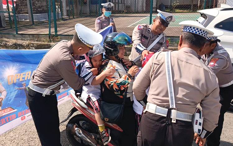 Petugas Satlantas Polres Barito Timur saat memberikan helm gratis kepada anak kecil yang tidak mengenakan helm, Kamis, 25 Juli 2024. (FOTO: IST)