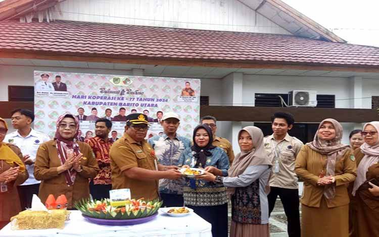 Kepala Disnakertranskop UKM Kabupaten Barito Utara, M Mastur menyerahkan nasi tumpeng peringatan Hari Koperasi ke 77 tahun 2024 kepada salah satu Ketua Koperasi Parajakian Mahyudin di Desa Lemo II Kecamatan Teweh Tengah, Senin 29 Juli 2024.(foto: Dhani)