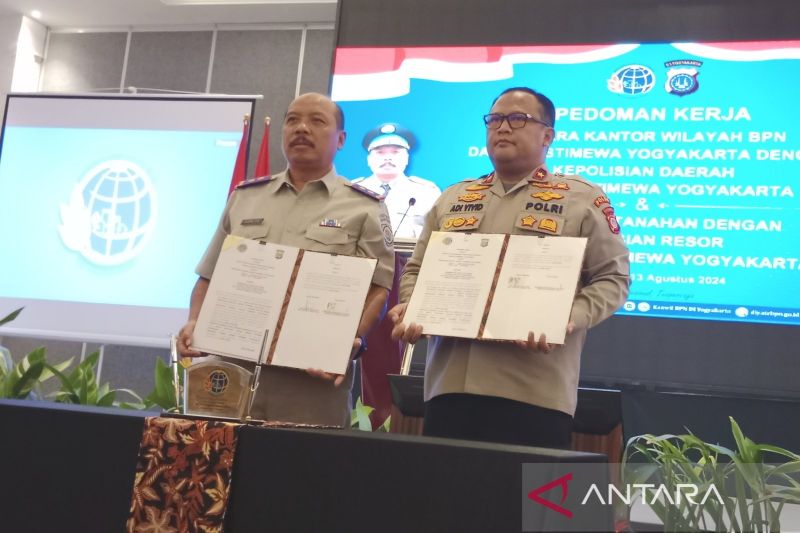Kepala Kanwil BPN DIY Suwito (kiri) bersama Wakapolda DIY Brigjen Pol. Adi Vivid Agustiadi Bachtiar menunjukkan dokumen pedoman kerja penanganan masalah pertanahan yang ditandatangani keduanya di Yogyakarta, Selasa (13/8/2024) (ANTARA/Luqman Hakim)