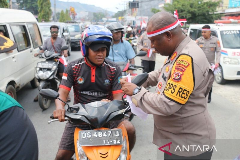 Kapolres Jayapura AKBP Umar Nasatekay saat membagikan bendera merah putih kepada masyarakat yang melintas dengan menggunakan kendaraan roda dua pada Selasa. (ANTARA/Yudhi Efendi)