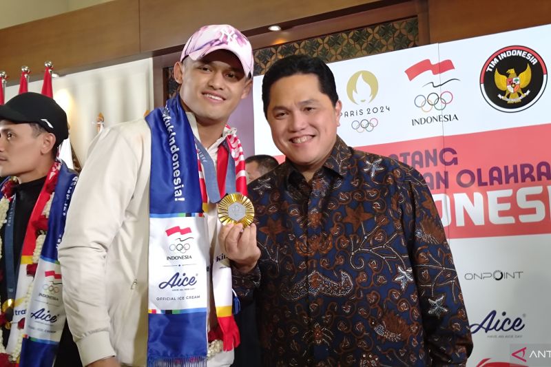 Menteri Badan Usaha Milik Negara (BUMN) Erick Thohir saat menunjukkan medali emas yang diraih atlet angkat besi Rizki Juniansyah. (ANTARA/Azmi Samsul Maarif)