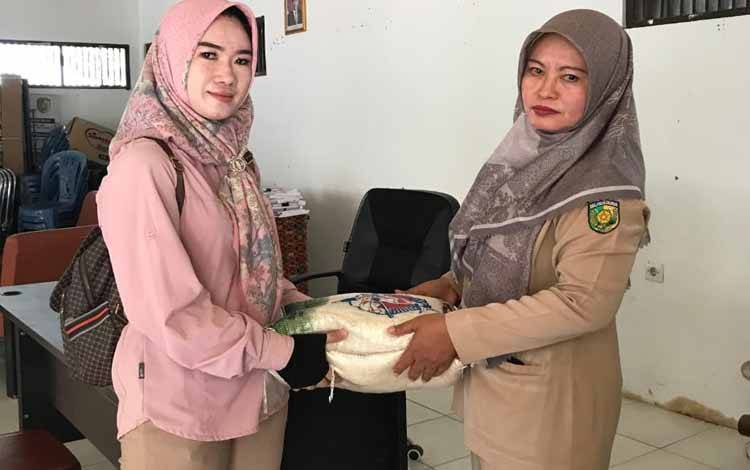 Kasi Kesos Kelurahan Panarung Sri Lestari saat menyerahkan bantuan beras kepada kader posyandu (Foto : PATHUR)