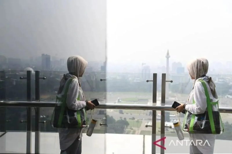 Arsip foto - Seorang wanita melintas dengan latar belakang Monas yang tertutup polusi di Jakarta, Jumat (21/6/2024). ANTARA FOTO/Akbar Nugroho Gumay