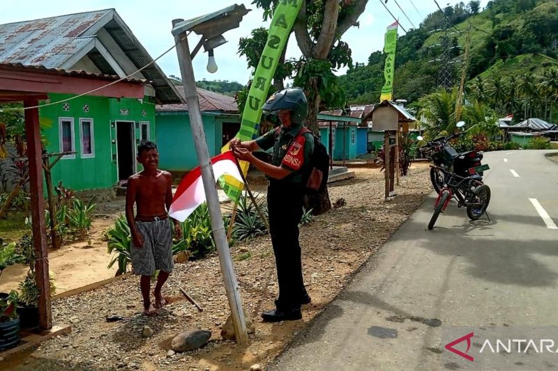 Aparat Babinsa Koramil 1314-01/Kwandang Gorontalo Utara membantu warga memasang bendera Merah Putih di halaman rumah dalam memperingati HUT Ke-79 RI. (ANTARA/Susanti Sako)